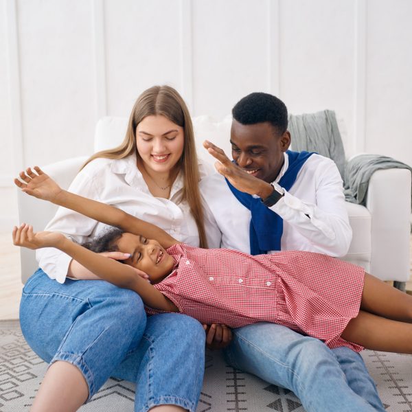 Happy family leisures in living room. Mother, father and their daughter poses at home together, good relationship