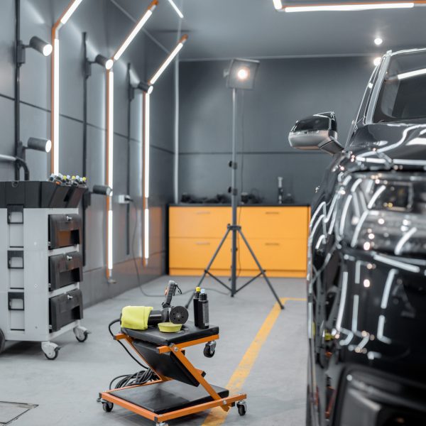 Car service station with luxury car prepared for the body polishing. Concept of car detailing and care