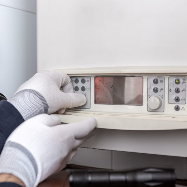 Technician servicing heating boiler in a house. Maintenance concept